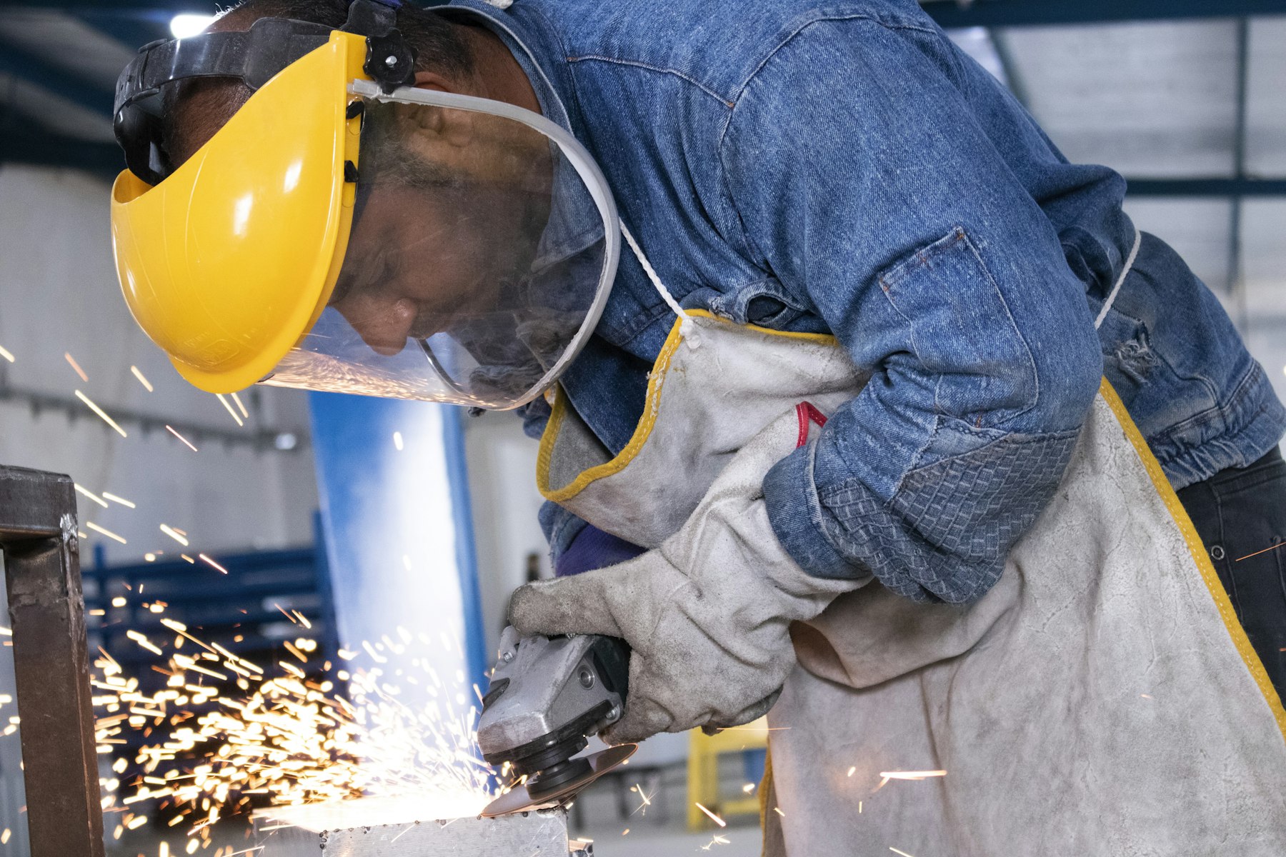 Metalworker grinding steel behind a face shield