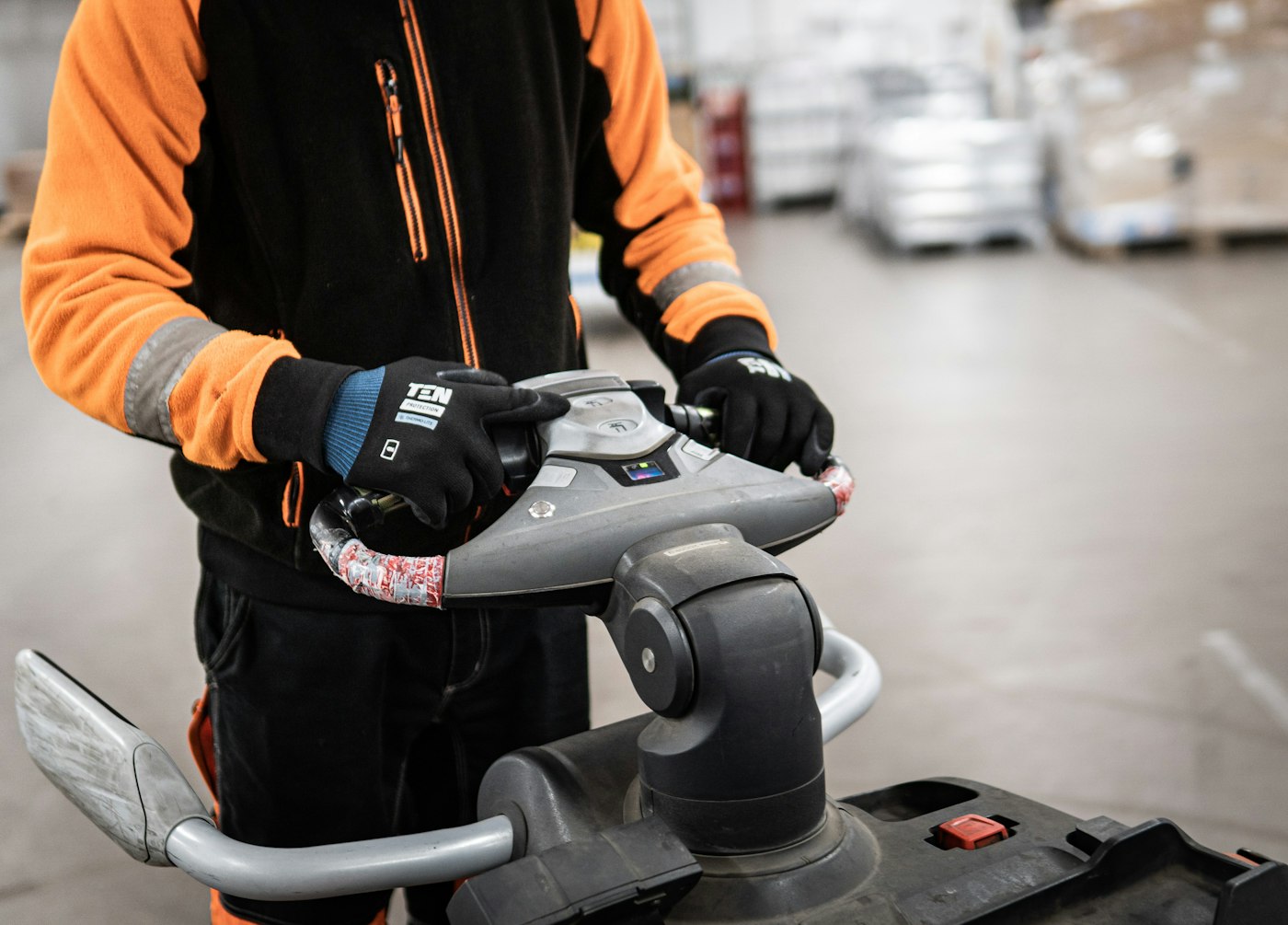Operator's hands on the controls of an electric pallet jack